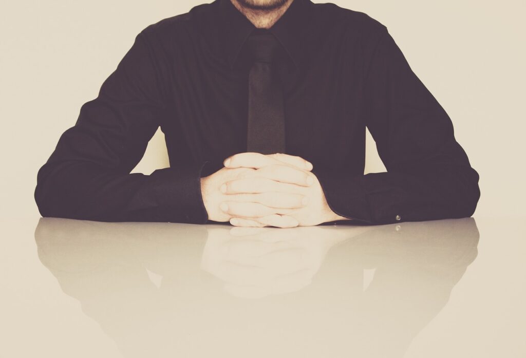 Man seated behind a desk appearing distressed, illustrating the emotional impact of workplace harassment. He is in need of a workplace harassment lawyer.
