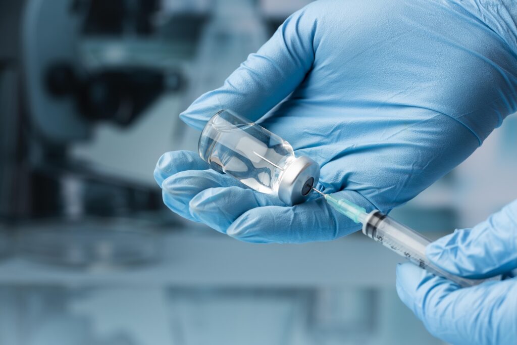 picture shows a lab worker in blue gloved handling a vaccine for study